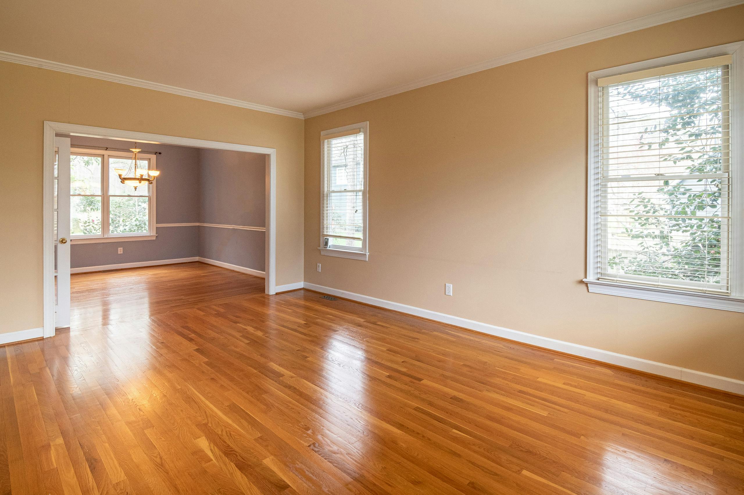 Bright empty room with wooden floors and large windows, ideal for real estate listings.