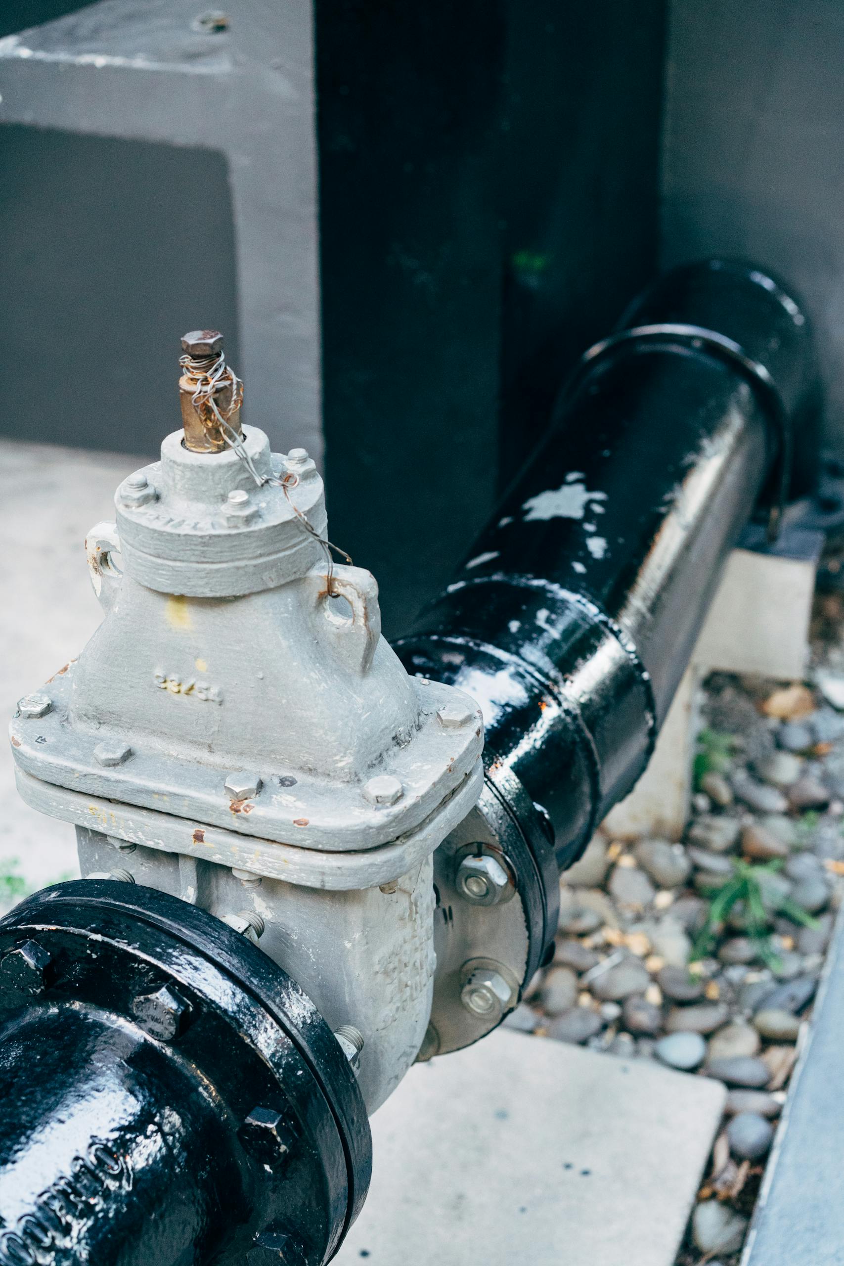 Detailed view of a plumbing valve with connected black pipeline, essential for industrial applications.